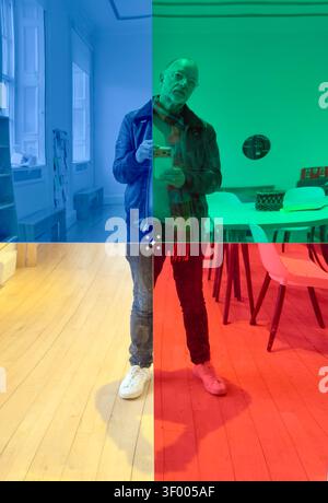 Man taking a selfie in an indoor space with blue, green, yellow & red color overlay quadrants Stock Photo