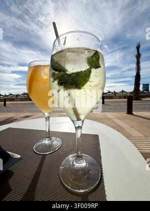 Two refreshing cocktails on an outdoor table near a beach promenade on a sunny day Stock Photo
