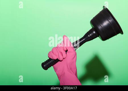 Close-up of a gloved hand holding a rubber plunger. Plumbing and maintenance works in home. Problems and solutions chore. Stock Photo