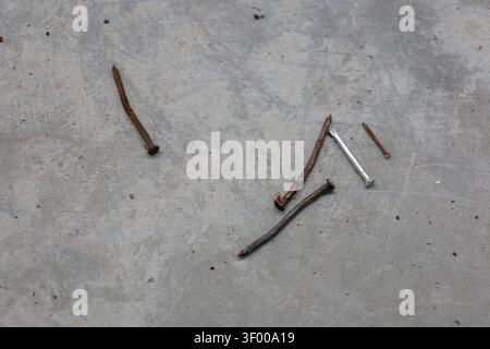 Rusty Bent Nails on Concrete Floor Showing Contrast Between Old and New Construction Materials Stock Photo