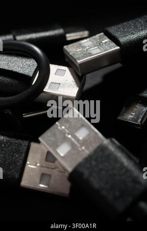 Close-up of a group of coiled black USB-C to USB-A cables. They are used for fast data transfer and charging of electronic devices. Network connectors Stock Photo