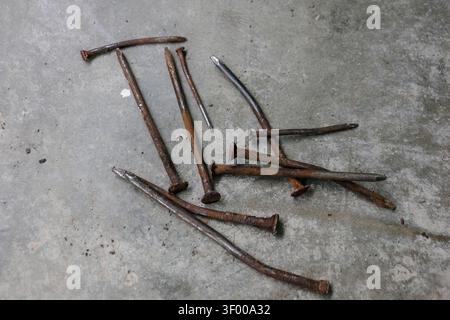 Rusty Bent Nails on Concrete Floor Showing Contrast Between Old and New Construction Materials Stock Photo