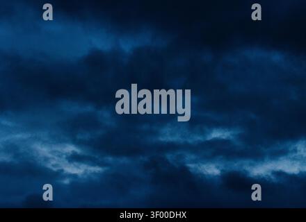 Dark blue storm clouds fill the sky over Corona with a moody evening atmosphere. Stock Photo