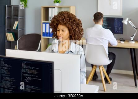 Female software developer coding at desktop in modern office workspace environment Stock Photo