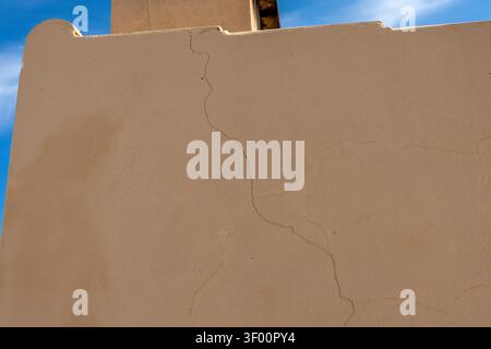 Detailed view of hairline cracks and imperfections on a textured beige exterior wall under a clear sky Stock Photo