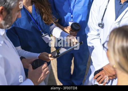 Medical team of doctors and nurses collaborating, reviewing data on a digital tablet, and discussing patient cases, symbolizing teamwork, innovation, Stock Photo