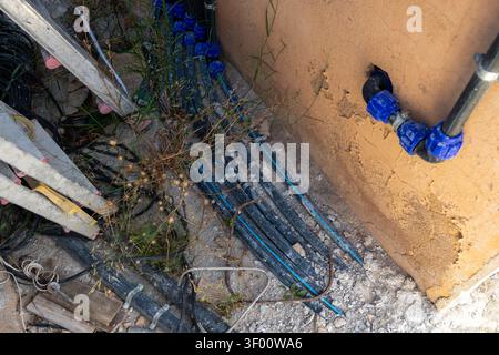 A messy construction site featuring various plumbing pipes and electrical wires alongside a ladder and building materials Stock Photo