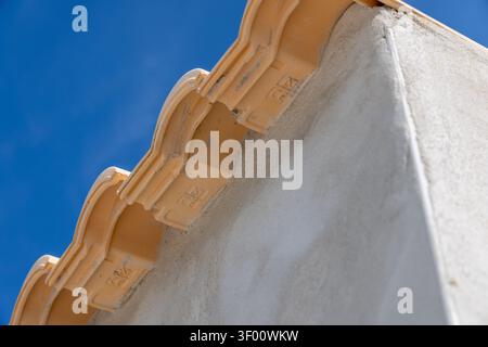Detailed shot of overlapping terracotta roof tiles showing their texture and markings, set against a vibrant blue sky Stock Photo