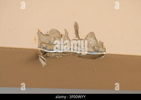 A detailed view shows a section of wall where the plaster has chipped away, exposing a wire mesh reinforcement and the substrate beneath Stock Photo