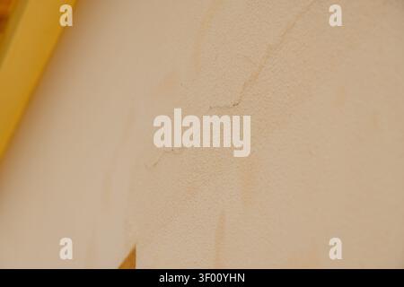 A detailed abstract texture of a damaged wall showing hairline cracks and discoloration, suggesting age or water damage Stock Photo