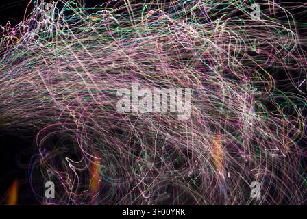 Time exposure of fireworks and lights at a fairgrounds at night. Image shows the paths, patterns, tracks, loops, spirals and colors in the fireworks a Stock Photo