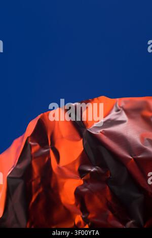 Vibrant abstract image featuring a crumpled orange foil surface against a deep blue background. The bright colors and textures create a striking visua Stock Photo