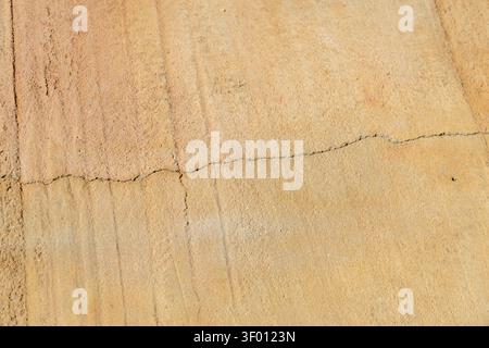 A detailed view of a weathered sandstone surface, showcasing its granular texture and a prominent linear fracture across the frame Stock Photo