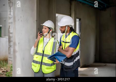 Civil construction manager inspects an unfinished residential construction project with civil engineer, reviewing list of defects on tablet while comm Stock Photo