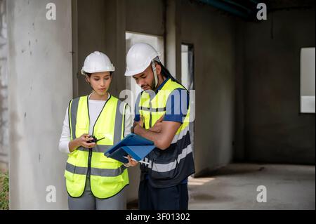 Civil construction managers inspecting unfinished residential building project with civil engineer, checking defect list in tablet, Concept of propert Stock Photo