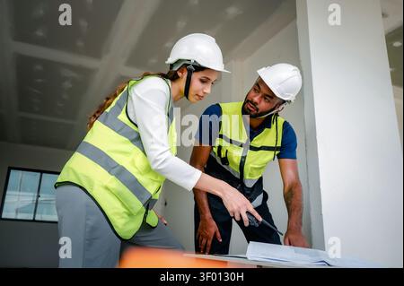 Construction Manager analyzing building blueprint indoor with Civil engineer while holding walkie talkie, scene for real estate property development a Stock Photo