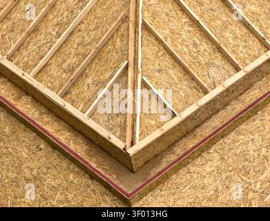 Close-up of a wooden roof under construction, showing truss framing and oriented strand board sheathing at a corner joint, highlighting carpentry and Stock Photo
