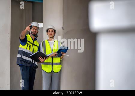 Two civil construction managers holding tablet and clipboard at residential construction site, inspection unfinished residential building inside, Hous Stock Photo