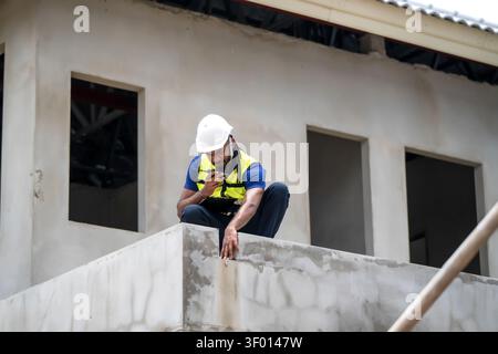 African American civil engineer holding walkie talkie and clipboard inspecting Structure concrete on residential building site during daytime, scene f Stock Photo
