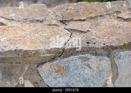 Detailed view of rough, layered stone showing natural erosion and fracture lines, with a shallow depth of field Stock Photo