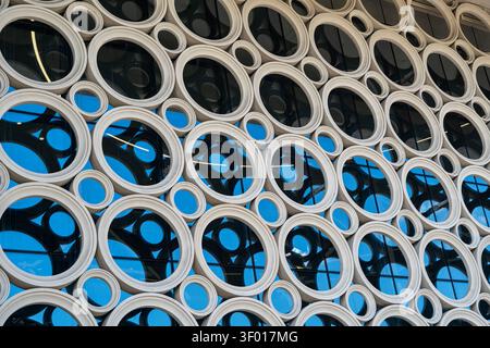 Abstract architectural facade featuring repeated circular frames and large glass windows, creating a geometric pattern with reflections and blue tones Stock Photo