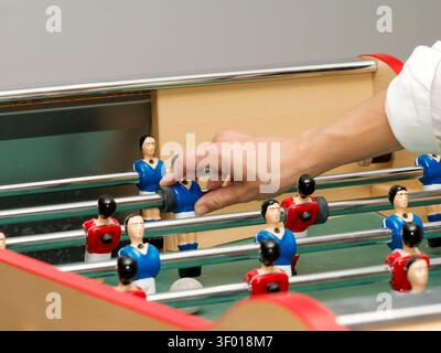 People playing table football with red and blue foosball figures at an indoor event Stock Photo