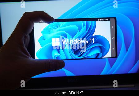 CHICAGO, IL, USA - JULY 15, 2021: A close-up image shows a hand holding a smartphone with the Windows 11 logo prominently displayed on the screen. The Stock Photo