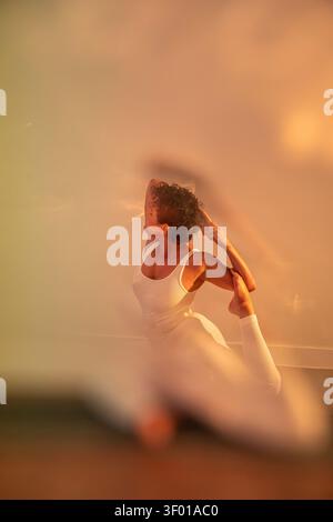 Latin woman practicing a deep backbend yoga pose on a mat in warm golden light. Soft focus foreground creates a calm, dreamy mood for wellness and min Stock Photo