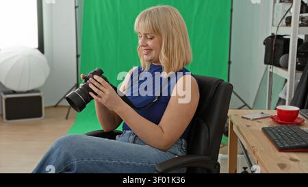 Woman holding dslr camera checking photos on the camera screen in a studio with green screen and lighting setup; creative calm. Stock Photo