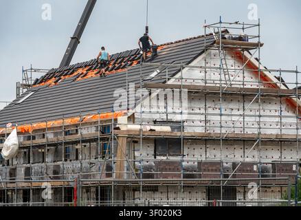 Tile roofing installation on new home under construction, roof work with builders and scaffolding Stock Photo