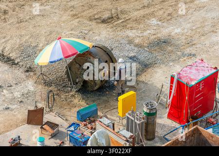Construction worker performing welding work with large steel casing pipe at construction site in Busan, South Korea. Heavy industry, civil engineering Stock Photo