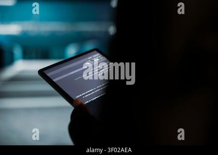Data center engineer uses a digital tablet in a data center to run hardware diagnostics and maintain operational stability. Stock Photo