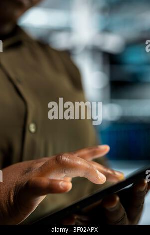 Data center administrator uses a tablet to expand workload capacity, supporting reliable infrastructure operations. Stock Photo