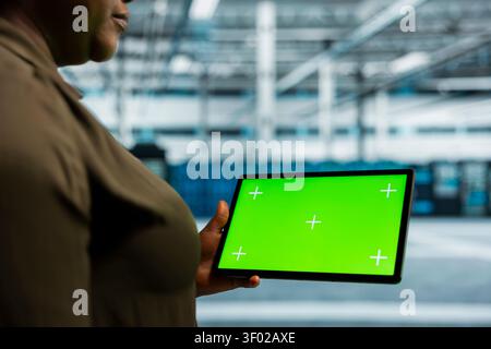 Data center administrator works with a chroma key tablet, using an editable screen to monitor anomaly detection. Stock Photo