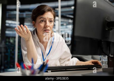 Concerned server hall worker sees error popup on screen while working with software. Stock Photo