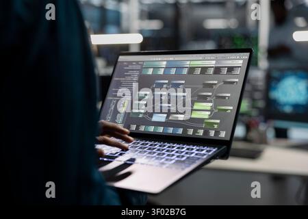 Data center engineer uses a laptop to manage machine learning workloads, working with AI technology and high performance systems. Stock Photo