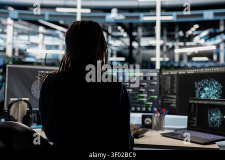 Data center technician uses a desktop computer in a data center to support automation monitoring and reliable server workflows. Stock Photo