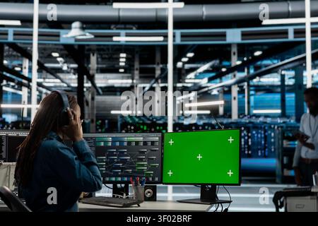 Data center worker works with a chroma key computer, using an editable screen to review performance data. Stock Photo