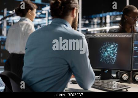 IT specialist uses a desktop computer in a data center to manage AI systems and optimize server infrastructure. Stock Photo