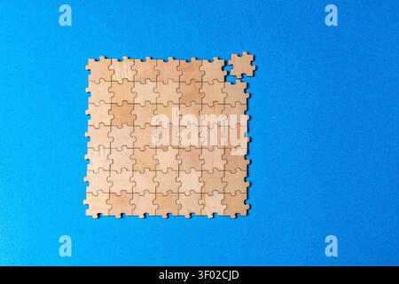 Wooden jigsaw puzzle missing one piece on blue background Stock Photo