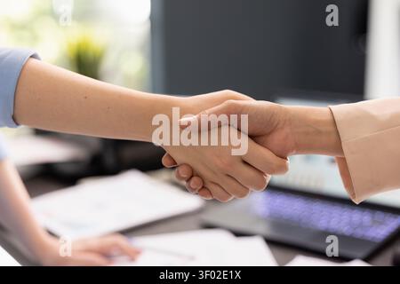 Closeup of handshake between two professionals in office, showing mutual agreement and cooperation. Colleagues shake hands after successful meeting, confirming alignment and shared goals in workplace. Stock Photo