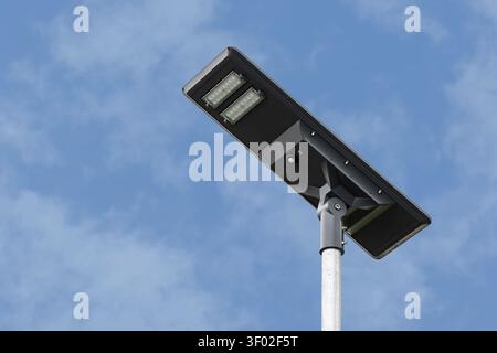 Modern solar powered LED street lighting unit with integrated photovoltaic panel and motion sensor, providing off-grid public lighting using renewable Stock Photo