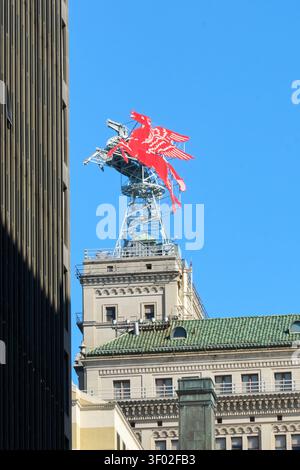 DALLAS, TX, USA - FEBRUARY 16, 2024: The iconic red Pegasus sign, a symbol of Dallas, is prominently displayed atop a historic building. Surrounded by Stock Photo