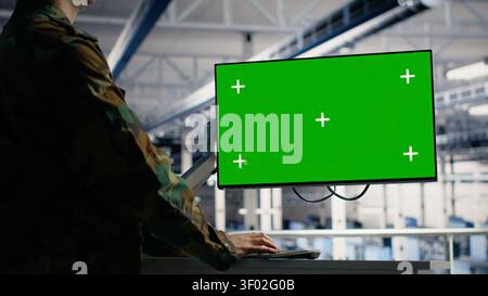 Military IT specialist reviews reconnaissance information on a green screen computer inside a server room. Stock Photo