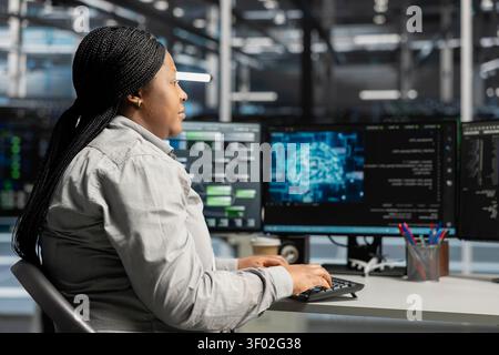 Server facility computing specialist applying AI neural network models technology. Woman working in data center working with AI programming tools on workstation, setting up specialized hardware. Stock Photo