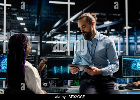 Manager and trainee tunes AI model settings on a computer workstation in a server room to improve systems. Stock Photo