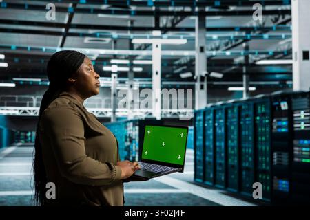 Data center administrator works with a chroma key laptop, using an editable screen to monitor anomaly detection. Stock Photo