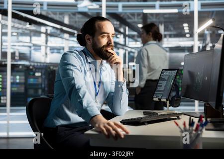 System administrator working with computer in server facility, managing server virtualization, running scripts. Stock Photo