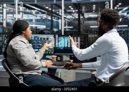 Data center software developers working together applying AI to reduce downtime. Workplace coworkers design and roll out AI driven solutions for server facility equipment. Stock Photo