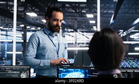 Data center manager oversees programmers reviewing AI diagnostics and machine learning systems. Stock Photo